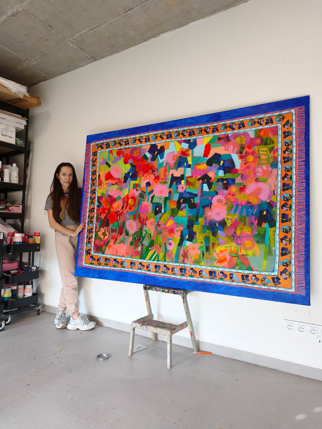 Artist standing next to large abstract floral painting Iris Meadow in contemporary art studio
