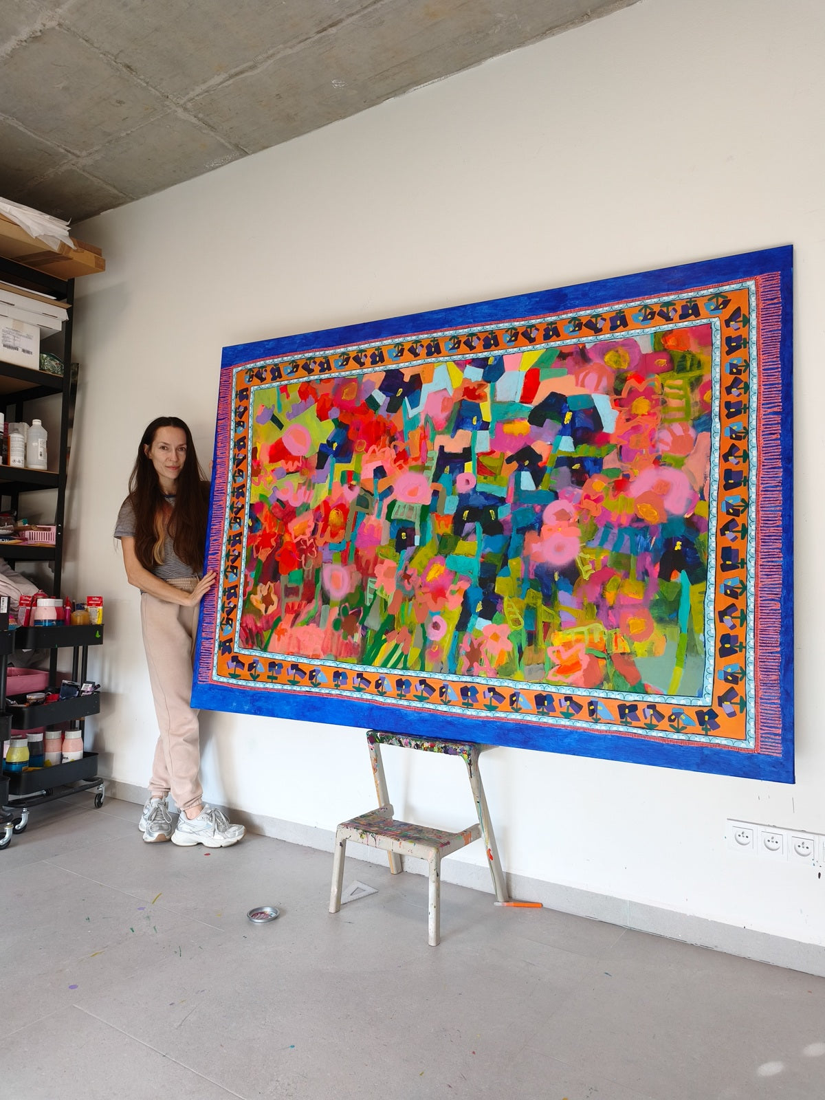 Artist standing next to large abstract floral painting Iris Meadow in contemporary art studio