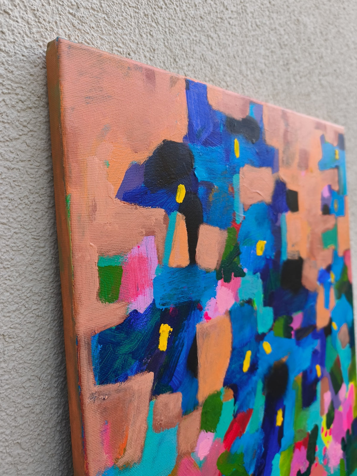 Close-up of abstract floral wall art with blue iris flowers and soft pink floral elements on orange background