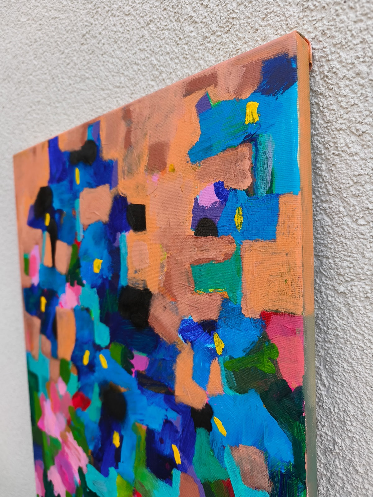 Textured detail of small abstract painting with layered acrylic paint, pink flowers and expressive brushstrokes